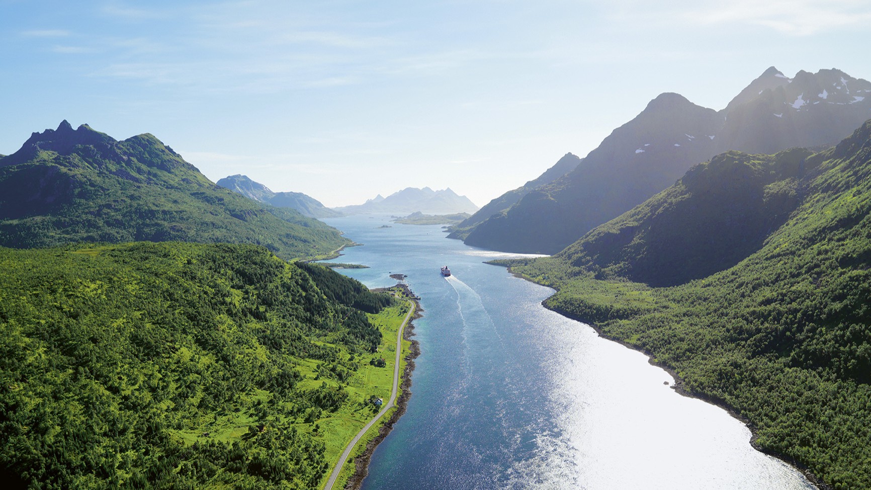 Hurtigruten Schiff fährt entlang der norwegischen Küste bei strahlendem Sonnenschein, vorbei an Fjorden und Bergen | © Hurtigruten