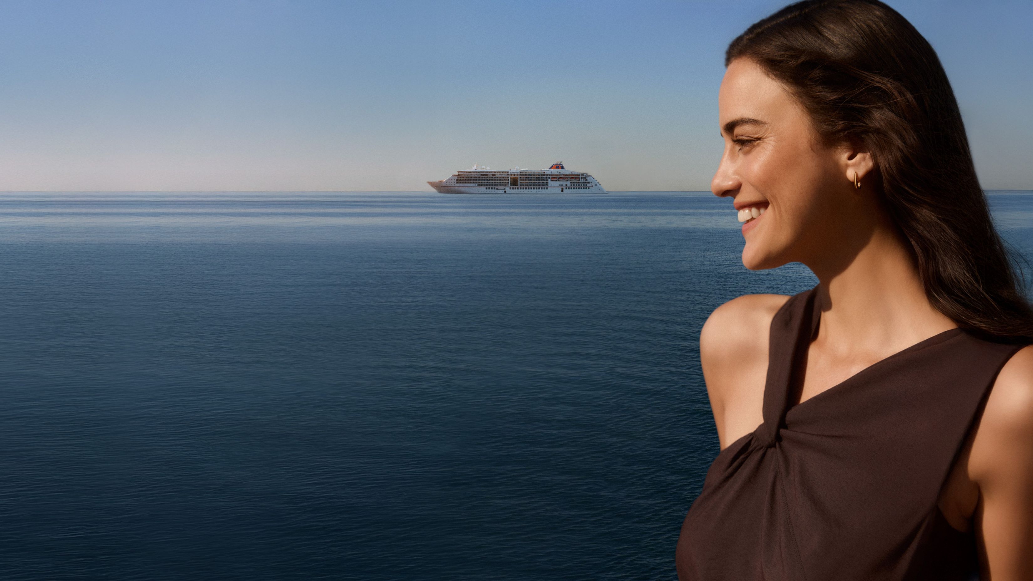 Lächelnde Frau und im Hintergrund ein Hapag-Lloyd Cruises Kreuzfahrtschiff | © Hapag-Lloyd Cruises