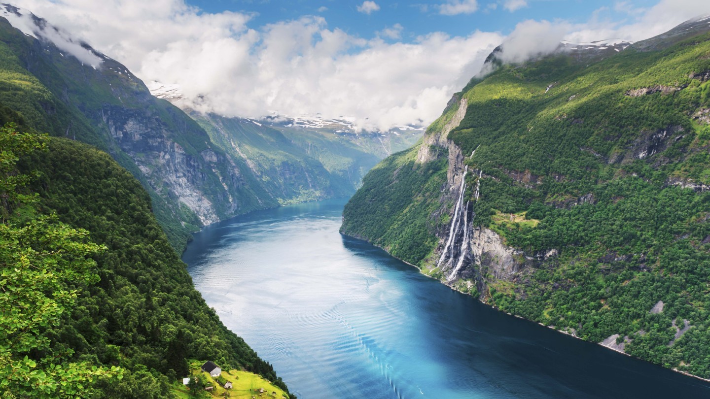 Fjord mit steilen, grünen Hängen, Wasserfällen und schneebedeckten Bergen im Hintergrund | © MSC Cruises